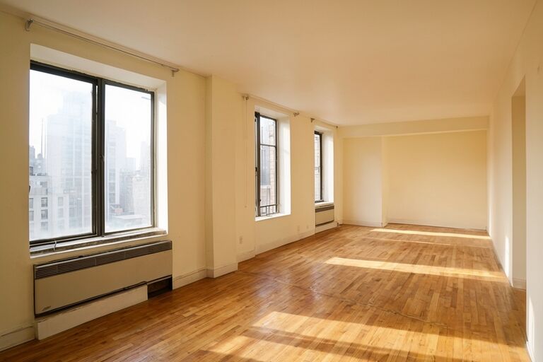 Clean empty Manhattan apartment with sunlit hardwood floors after cleanout