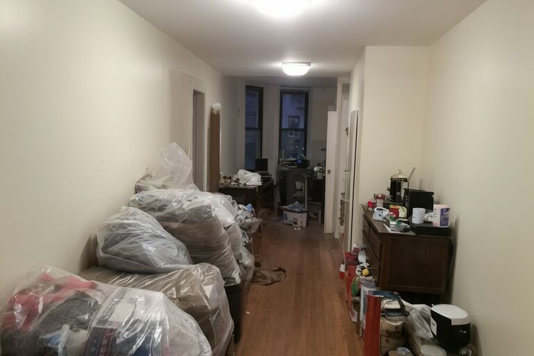 Small NYC apartment cluttered with leftover furniture and bags after move-out
