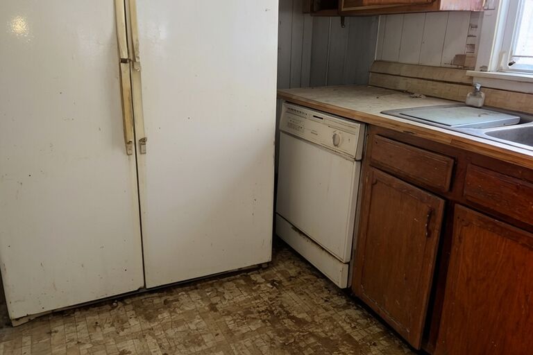 Old kitchen appliances including refrigerator and dishwasher awaiting removal