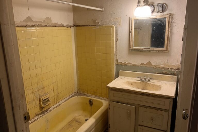 Outdated bathroom with old tile walls yellowed bathtub and dated vanity cabinet