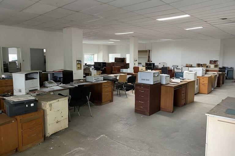 Commercial space filled with old office furniture and filing cabinets for removal
