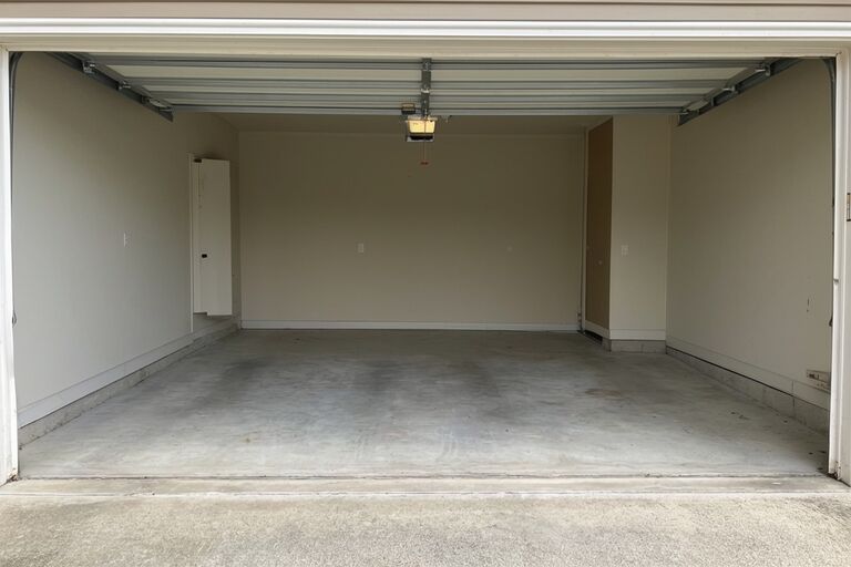 Clean empty two-car residential garage after complete cleanout with open door