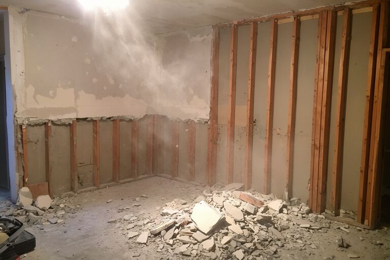 Partially demolished drywall exposing wooden stud framing in renovation site